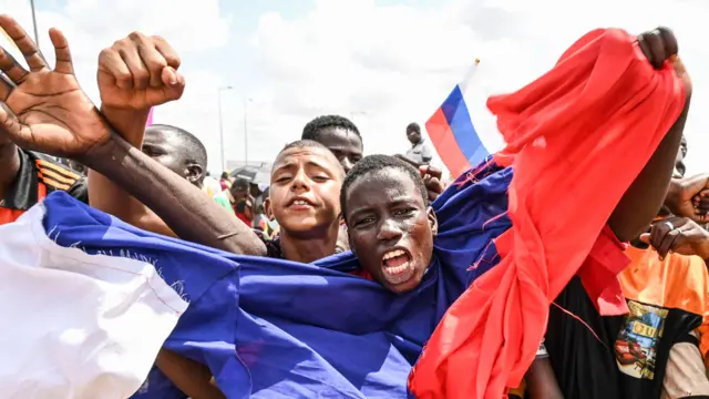 Manifestation pro-russe à Niamey en 2023 : un homme agite un drapeau russe devant des bases aériennes nigériennes et françaises.