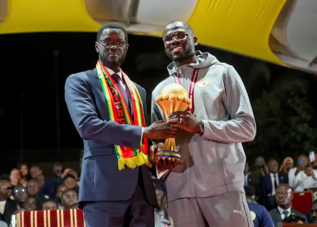 le président sénégalais Bassirou Diomaye Faye et le capitaine de l'équipe nationale du Sénégal, Khalidou Koulibaly, brandissent le trophée de la coupe d'Afrique des nations
