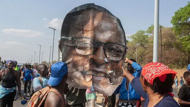 Un groupe de personnes brandit une image géante de la tête de Lazarus Chakwera qui a été arrachée d'un panneau d'affichage.