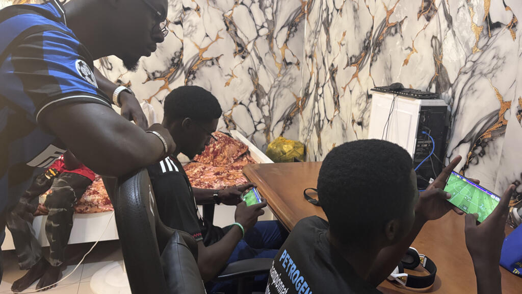 Un entraîneur et des joueurs sénégalais s'entraînant à l'eFootball sur smartphone à Dakar