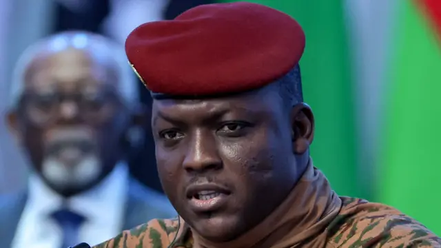 Portrait d'Ibrahim Traoré en tenue militaire beige et béret rouge, lors d'une intervention télévisée